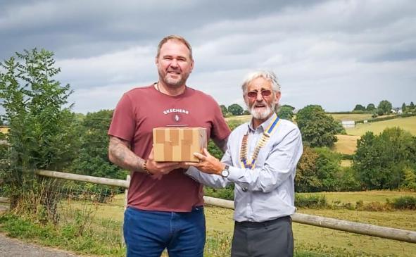 Rotary Club of Lyme Regis President Alan Vian receiving the first box of tea lights from Scott Quinnell